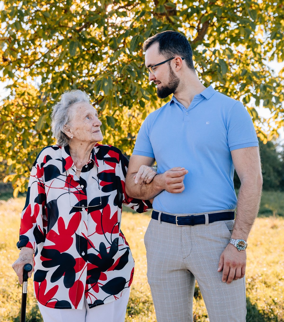 Markus Kösler beim Spaziergang mit einer Seniorin, die sich bei ihm eingehakt hat